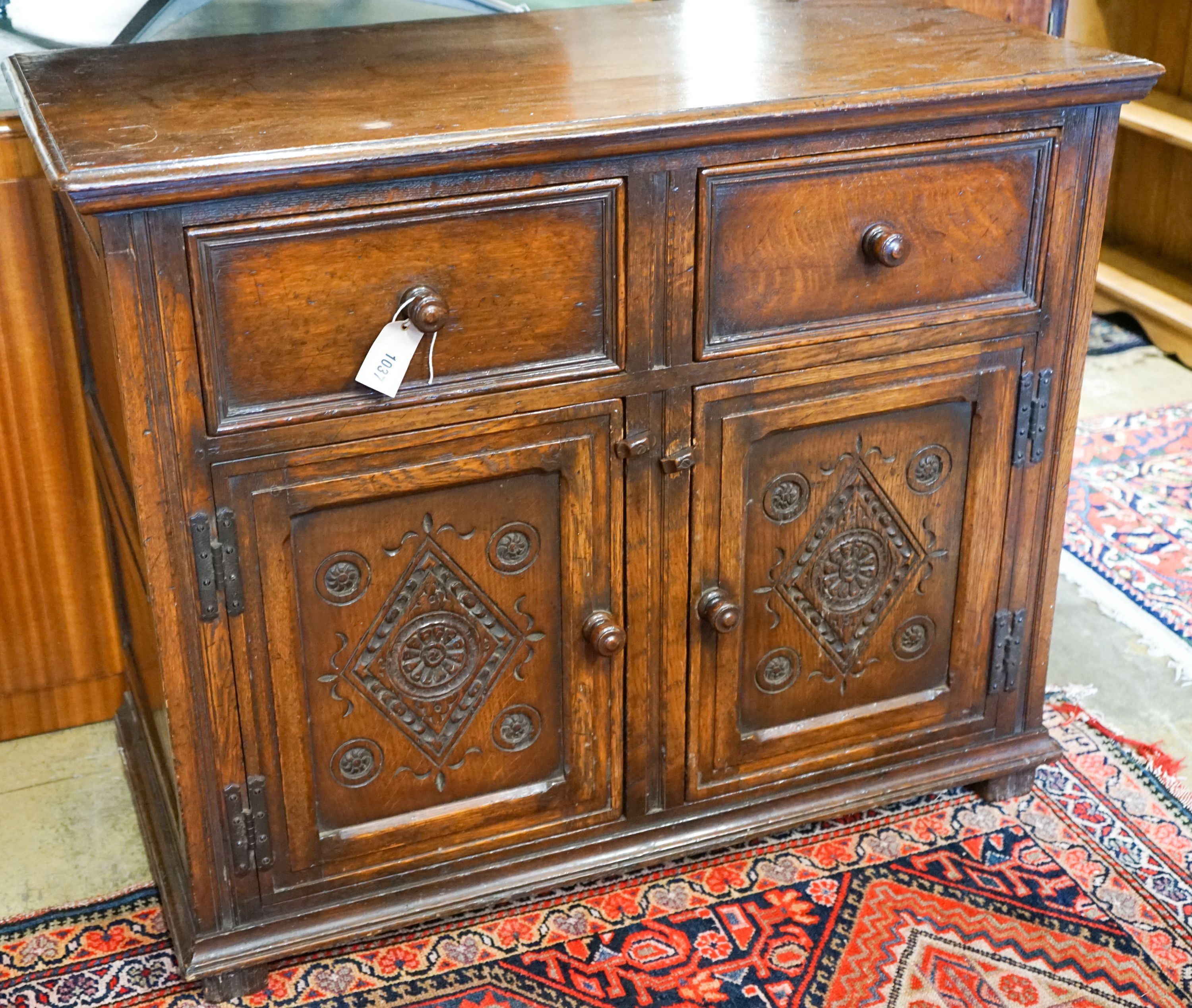 A 17th century style carved and panelled oak cupboard